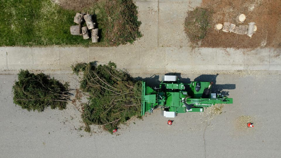 An aerial view of a wood chipper beside piles of cut brush